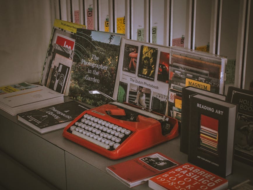 A vibrant red vintage typewriter surrounded by a collection of photobooks and literature in an artistic setup.